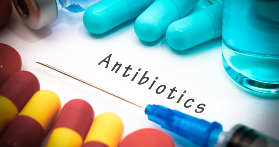 Antibiotika - Diagnose geschrieben auf einem weißen Blatt Papier. Spritze und Impfstoff mit Medikamenten.
