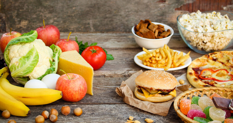 Fastfood and healthy food on old wooden background. Concept choosing correct nutrition or of junk eating.