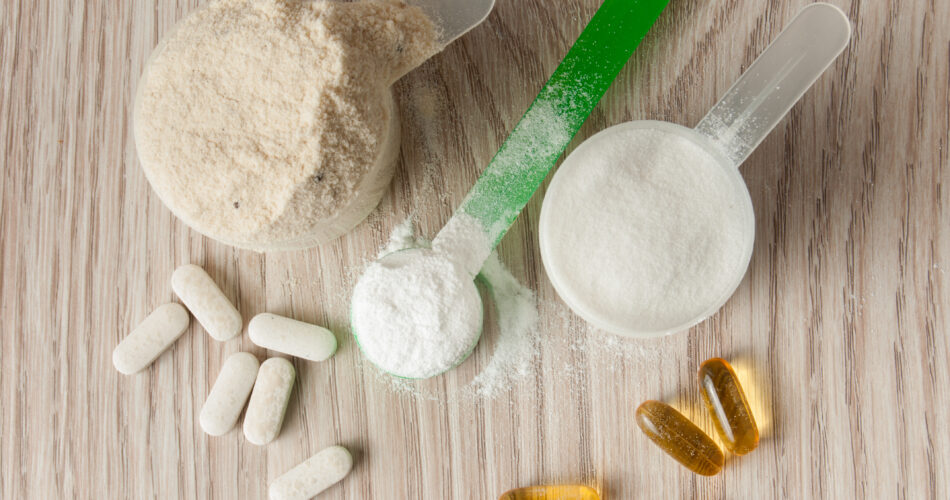 scoop of protein, bcaa and creatine, omega3 in pills on wooden background