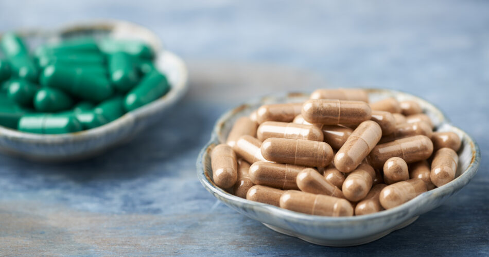 Green Tea and L - Carnitine capsules. Concept for a healthy dietary supplementation. Rustic wooden background. Copy space.