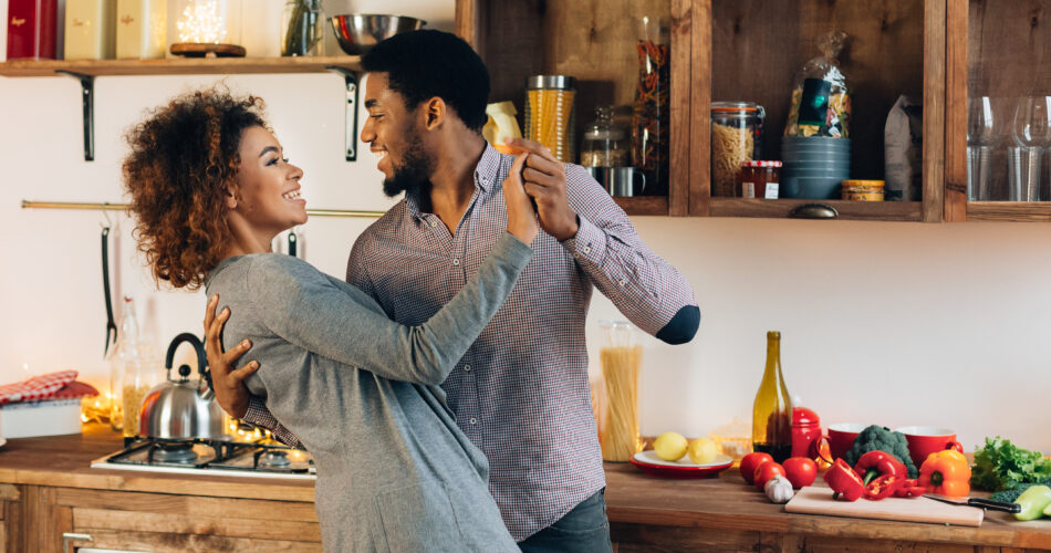 Happy moments. Young african-american couple in love dancing in kitchen, copy space