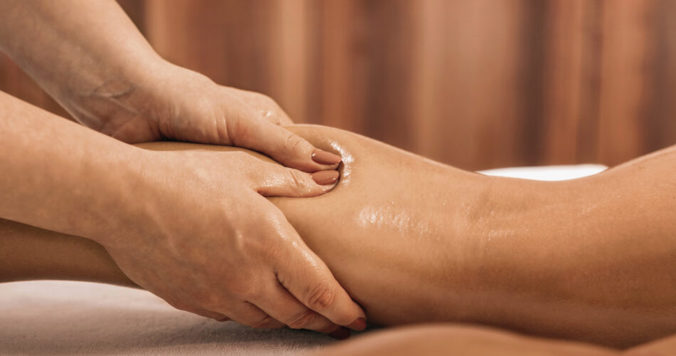 Lymphatic drainage massage. Hands of a masseuse massaging leg of a female client