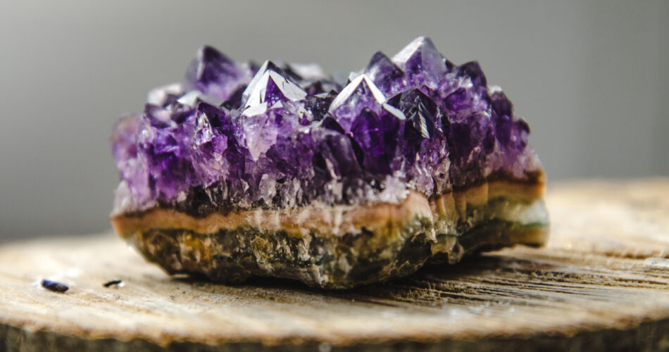 Raw violet amethyst rock with reflection on natural wood macro crystal  ametist esoteric