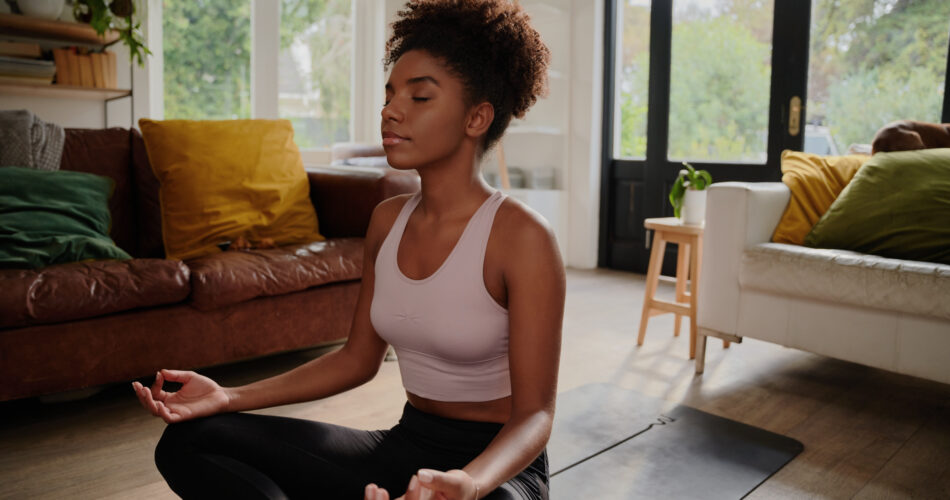 Young woman sitting on yoga mat meditating