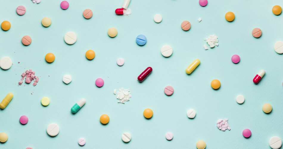 Una foto di diversi farmaci, compresse e pillole su sfondo blu.