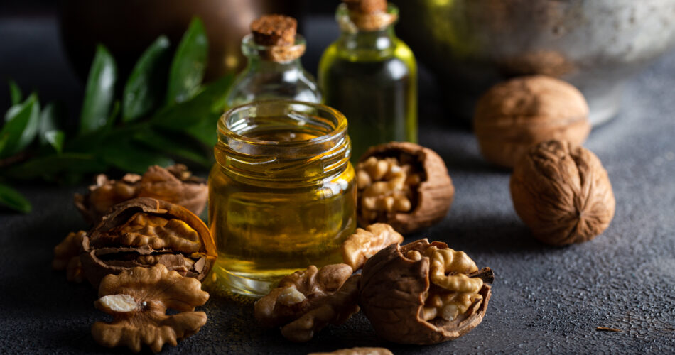 Cosmetic and therapeutic walnut oil on wooden background. Walnut oil in bottle and nuts on a dark background.
